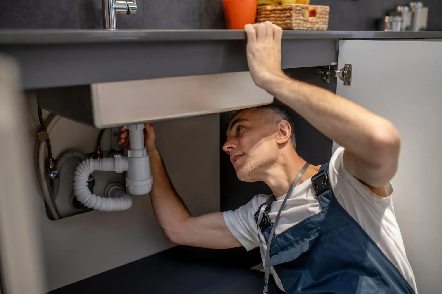 Experienced plumber examining the bottom of a kitchen sink